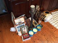 Photo showing candles, picture frames, metal candle holder, small decorative pieces on wooden floor.