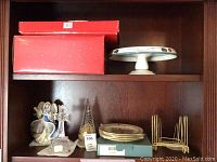 Overview of shelf with boxed items, serving plate and figurines showing full lot.