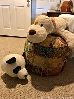 View of the pouf with the stuffed dog on top and panda head on the floor.