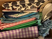 Box of folded fabrics including checkered, solid color fabric of various types