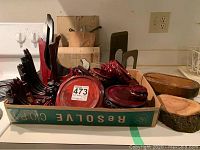Box holding multiple wooden plate and bowl holders in red lacquer, along with natural rustic wood bowl holders and other small display items.