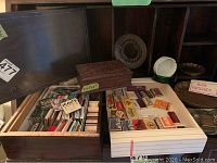 Overview photo of wooden box with lots of well-organized matchbooks inside, visible wear on box lid.