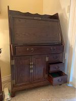 Full front view of wood secretary desk with drop-front writing surface closed, showing four drawers and two-door cabinet.