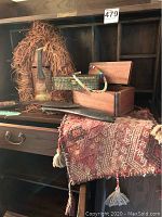 Overview of the collection showing the wooden African mask with woven straw, woven handbag on a wooden box, Burmese knife laying on a patterned rug.