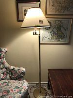 Full view of the brass standing floor lamp with the fabric shade on, showing its overall appearance and size relative to surrounding furniture.