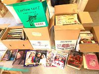 Boxes of assorted books on cooking, gardening, art history, and photography along with magazines spread out on the floor.