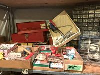 Full view of boxed and loose hardware items, red metal toolboxes, small hand tools, and plastic organizers on shelf.
