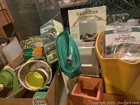 Overview showing bird feeder, sprinkler hose, terracotta pot, yellow container of plant fertilizer, and chicken wire rolls.