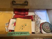 Drawer with assorted cloth napkins including floral embroidery and patterned fabric napkins