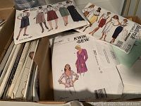 Photo showing several vintage sewing pattern envelopes with illustrations of women's clothing such as skirts and dresses, including Kwik Sew brand.