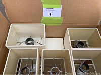 Top view of rectangular lamp shades inside cardboard box showing metal fittings.