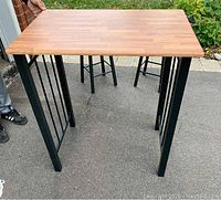Rectangular bamboo tabletop with black metal legs and vertical support bars, showing overall table construction