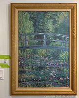 Full view of the framed painting showing bridge, water lilies, and dense green foliage.