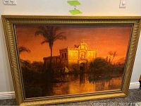 Full image of the framed wall art showing a sunset landscape with a historical building, palm trees, and water reflection.