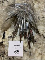 Multiple high-end silver icicle shaped Christmas ornaments in plastic bag showing pointed faceted design.