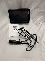 TomTom GPS device, charging cable with car adapter plug, and suction cup mount on a plain background.