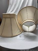Two beige fabric lamp shades placed side by side showing front and inner metal frame