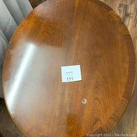 Top view of oval wooden night table showing wood grain, wear marks, and label with lot number 111.