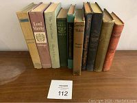 Front view of 10 antique books standing upright, showing spines and titles.