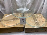 Three clear glass bowls of varying sizes arranged on cardboard boxes with MaxSold lot label visible.