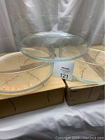 Three clear glass bowls stacked one inside the other showing their size and shape, sitting on cardboard boxes.