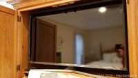 Front view of the Samsung flat screen TV powered off, showing screen and part of wooden cabinet in background.