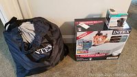 New Intex Dura-Beam Deluxe queen size air mattress in box with black Intex carry bag for used mattress and Intex electric pump box beside it