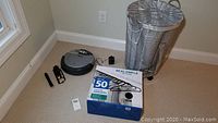 Full lot overview showing Roomba vacuum parts, box of hangers, wire hamper