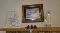 Framed watercolor artwork signed by Jerry Bishop showing swans, along with smaller framed flower painting, three red cardinal figurines, and two glass Galileo thermometers on shelf