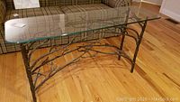 Full view of the sofa table showing the glass top and metal base with twig design.