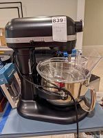 Front and side view of black KitchenAid Professional mixer on table with bowl and splash guard attached