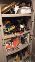 Storage shelf with various tools including boxed and loose items, power tools, and accessories.