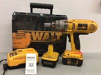 Overview of DeWalt cordless impact wrench, charger, extra battery and carrying case on table.
