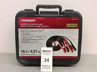 Closed black plastic carrying case with Husky branding and product specifications sticker describing 6 gauge 16 ft booster cable.