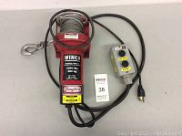 Dayton electric cable winch with attached wired remote control and power cord.