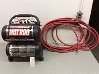 Front view of compressor and coiled red air hose