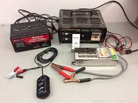 Full view of two MotoMaster battery chargers and vintage battery tester with cables and clamps.