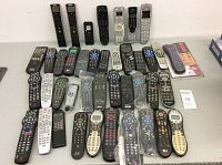 Overview of all assorted remote controls laid out on a flat white surface showing various sizes and shapes
