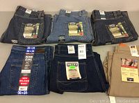 Six pairs of men's pants laid out: three Levi's Carpenter jeans, one Kirkland denim jean, one Smith's Carpenter jean and one Dockers khaki pant.