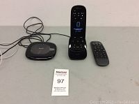 Three items on table: hub, touchscreen remote in dock, and standard remote