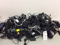 Pile of assorted power adapters, chargers, and cables on table
