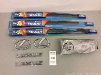Full lot showing three windshield wiper blades, two Lexus emblems and two Lexus lettering badges, plus spare tire cover bag
