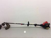 Side view of full weed wacker showing the long shaft, cutting guard, and handle