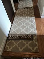 Three carpet runners placed on a hardwood floor in a hallway, showing overlapping runners with different patterns.