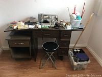 Overall view of sewing machine desk with sewing machine, stool, and craft supplies on and around it