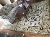 Two matching area rugs taped together, showing beige background and green floral patterned borders and central motifs.