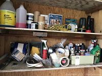 Shelf with assorted cleaning bottles, sprays, tapes, ropes, flashlights, motor oil and maintenance fluids.