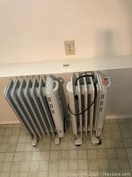 Front view of two oil-filled radiator heaters side by side against a wall