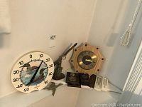 View of the entire lot including the thermometer, brass goose figurine, eagle sculpture, clock, and timer.
