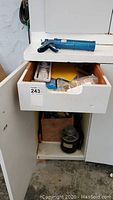 Inside white cabinet drawer showing soldering gun and assorted tools